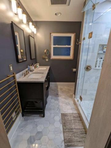 updated bathroom with blue walls and marble style flooring and tile