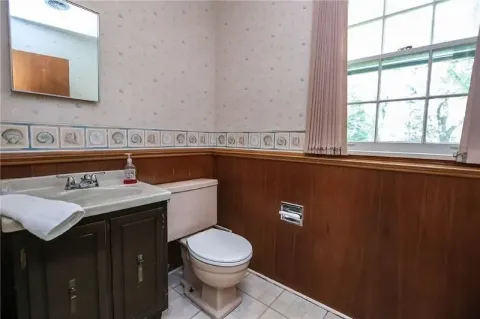 outdated bathroom with paneling and wallpaper