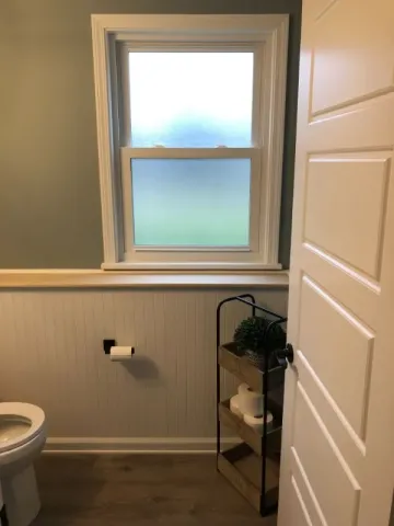updated bathroom with green walls and white paneling and accents
