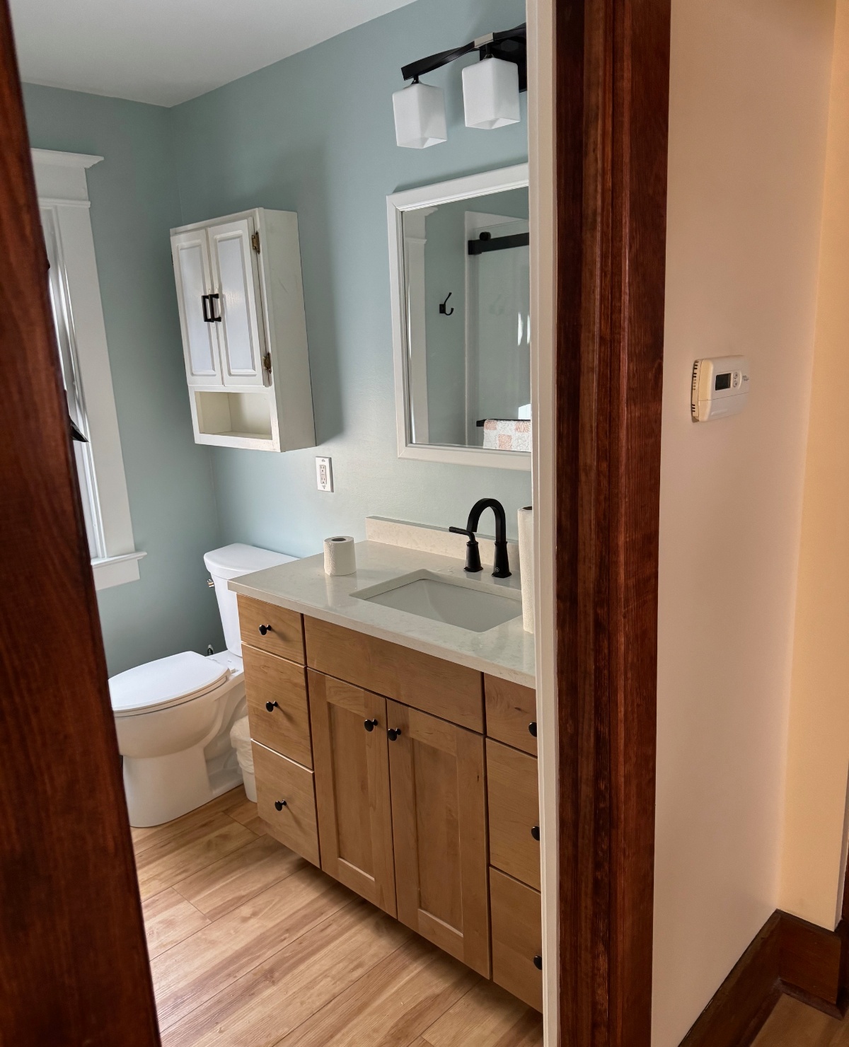 light blue bathroom with white and light wood accessories