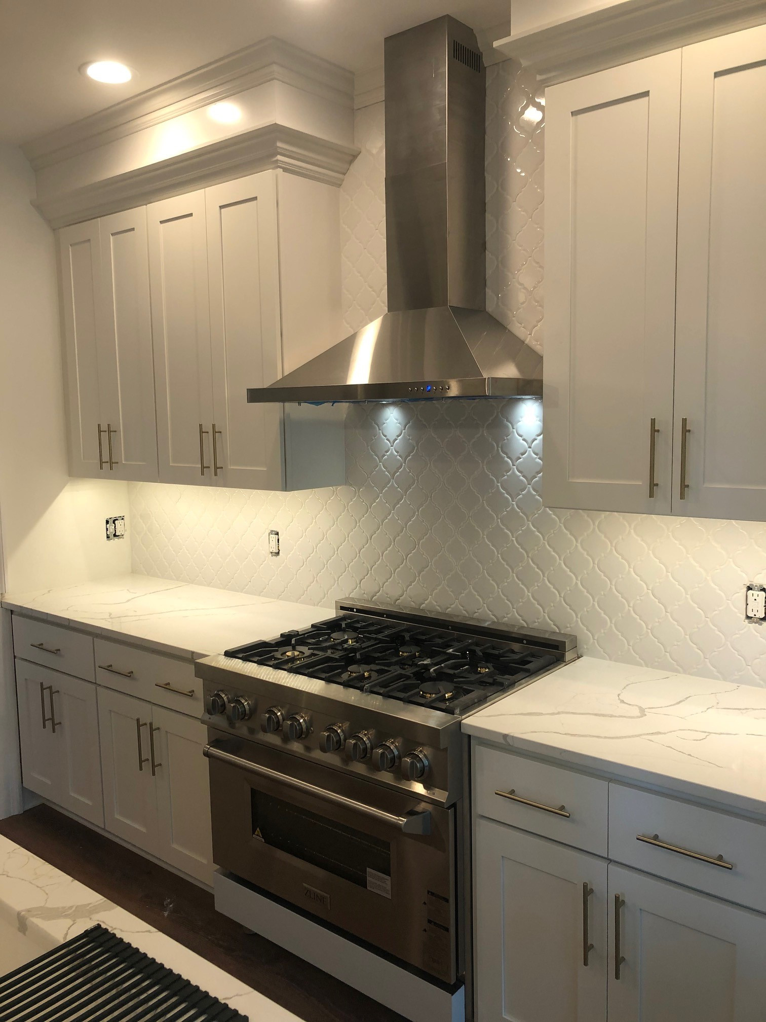 white kitchen with stainless steel stove and hood