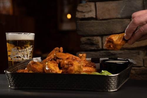 hand reaching into a plate of chicken wings