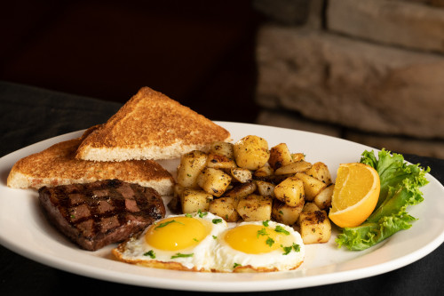 breakfast plate with steak eggs potatoes and toast
