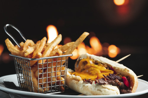 philly cheesesteak with a basket of fries
