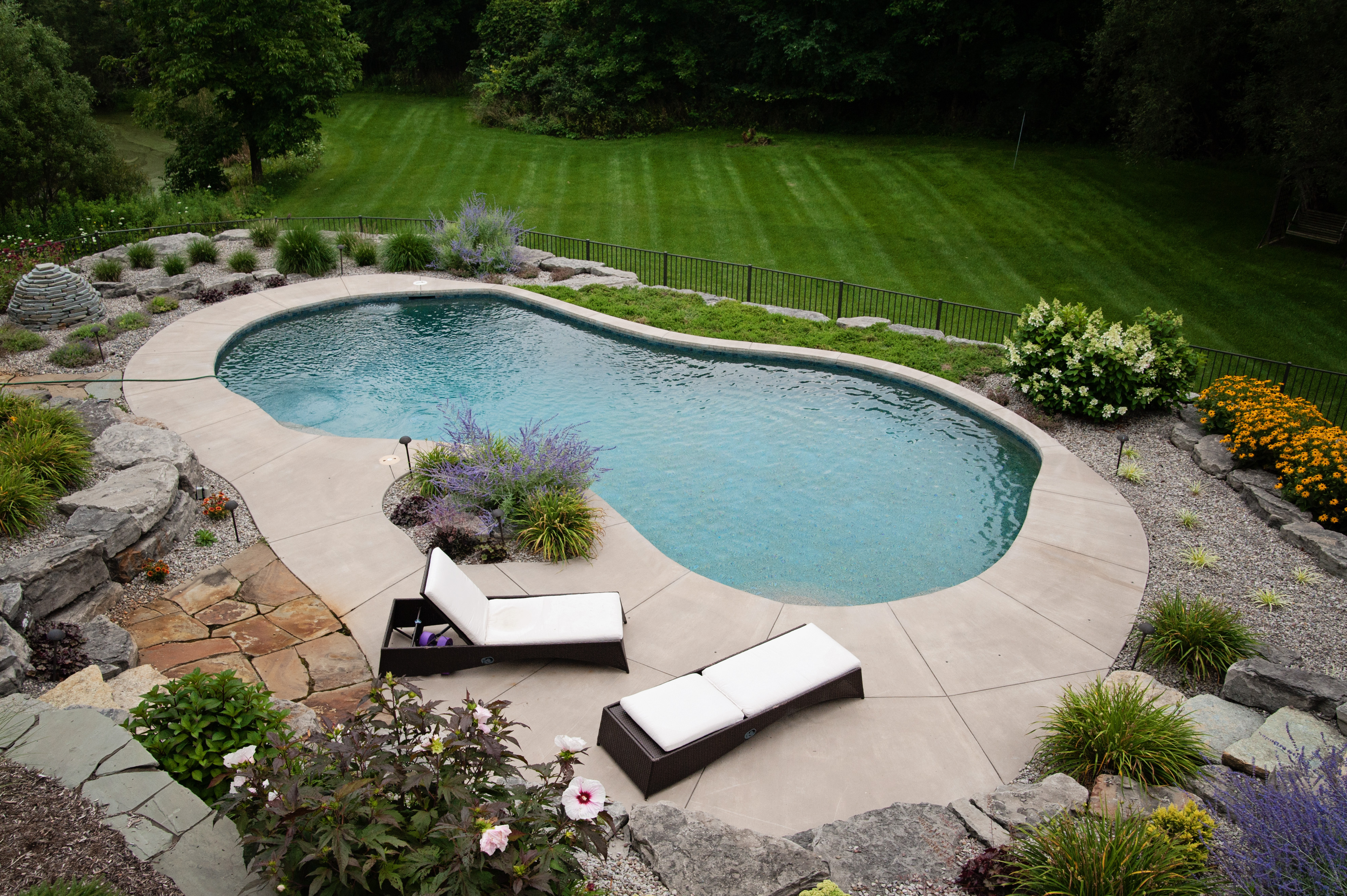 arial view of bean shaped pool surrounded by plants and stone hardscaping