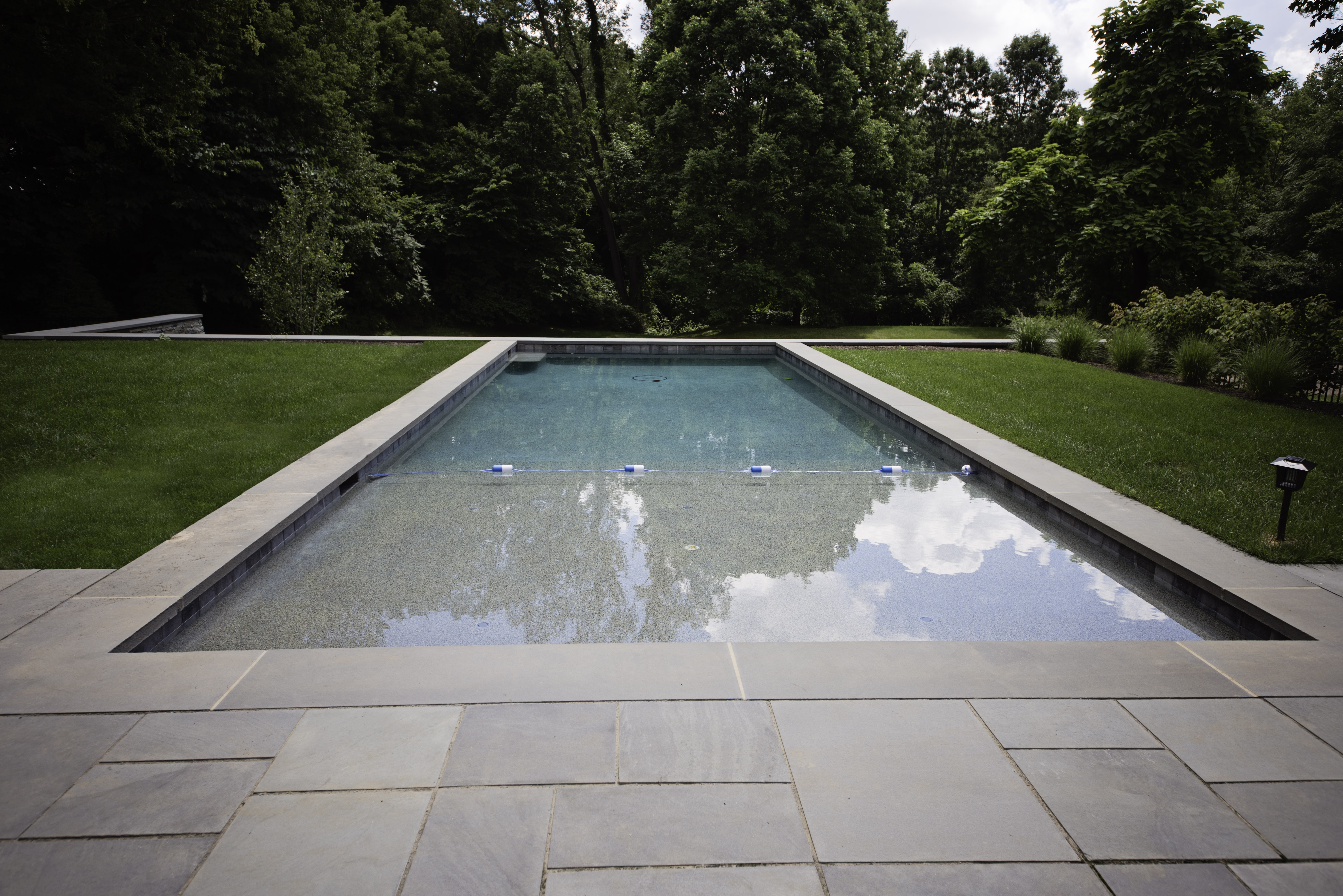 rectangular swimming pool with stone tile patio in front