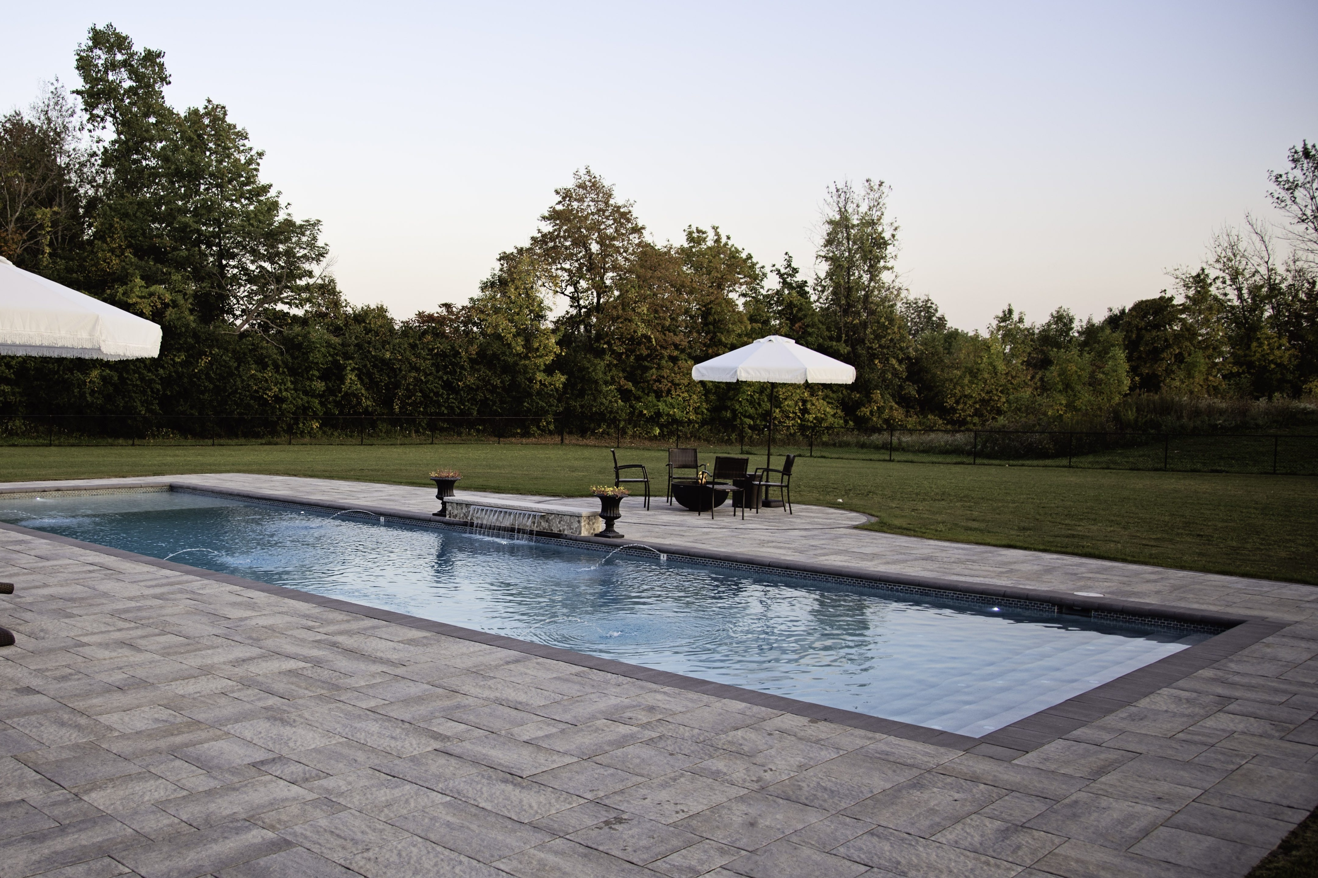 rectangular backyard pool with chairs and umbrellas