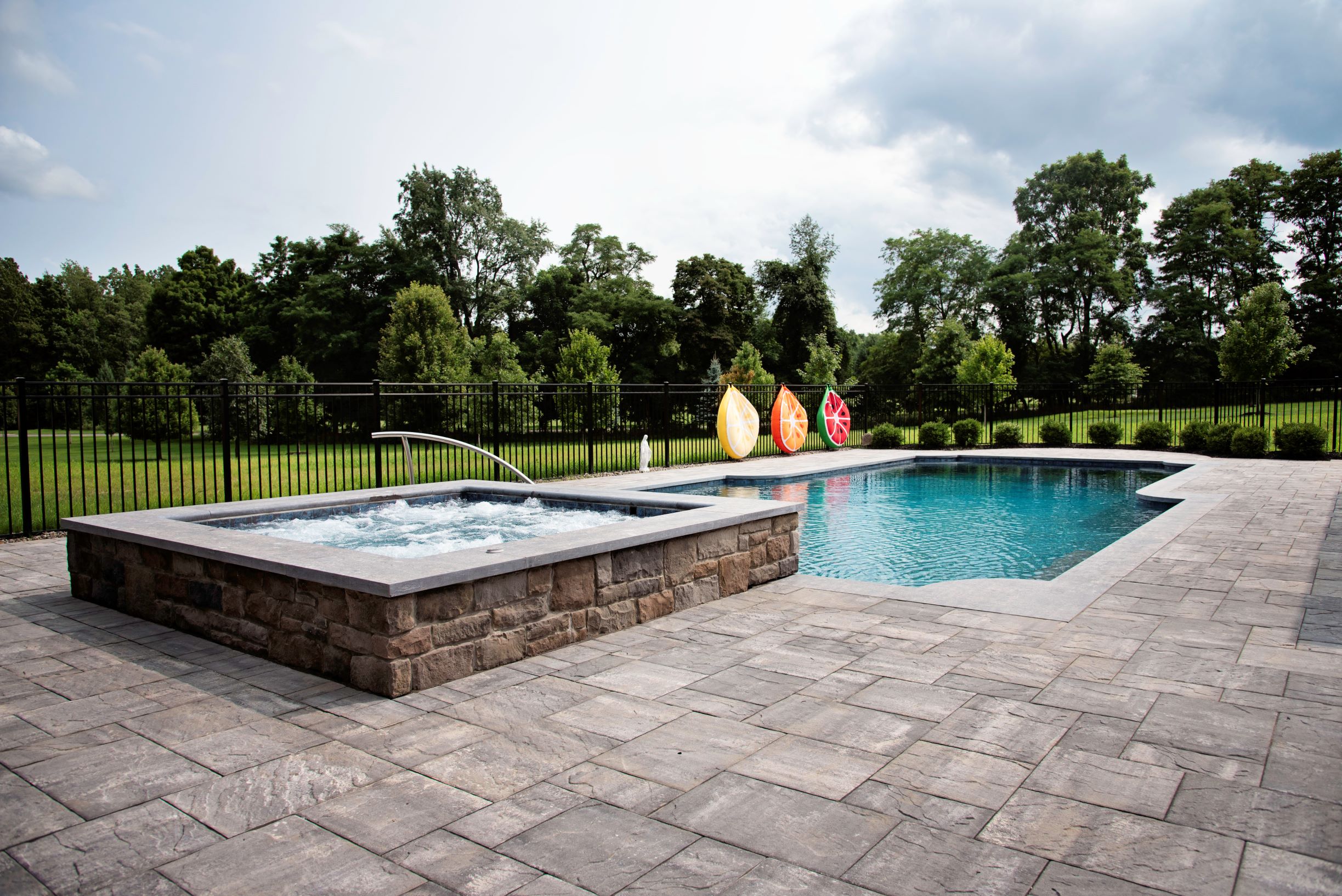 stone hot tub and swimming pool on a large patio