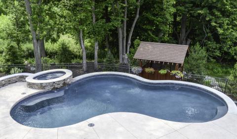 curved swimming pool and attached hot tub with stone edging