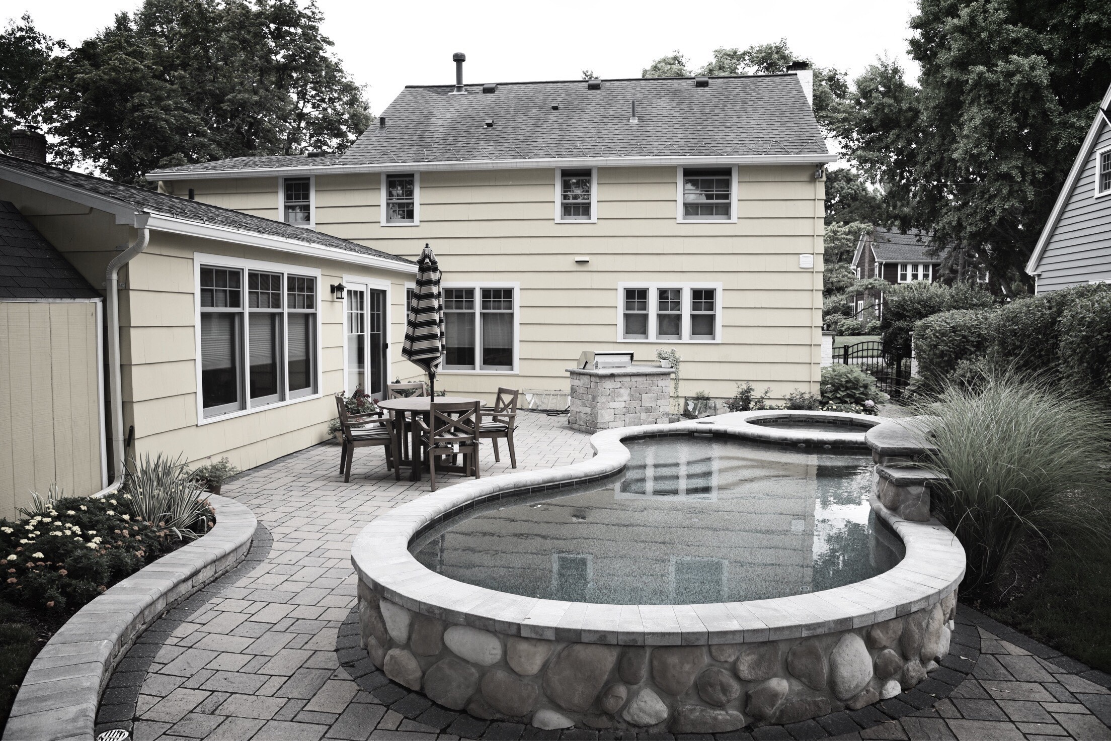 backyard with curved pool, spa, and patio table