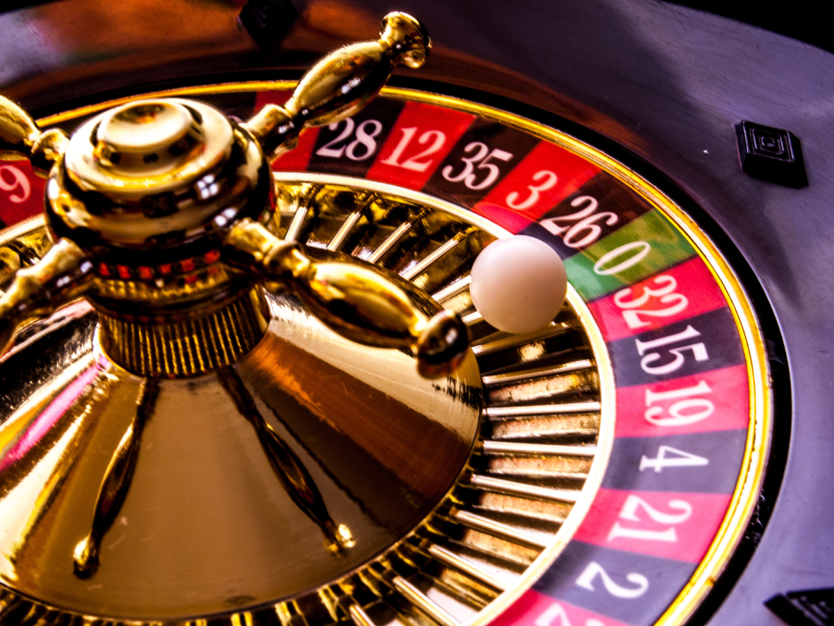 Close-up of a roulette wheel with a white ball landing on the number 26 red slot.