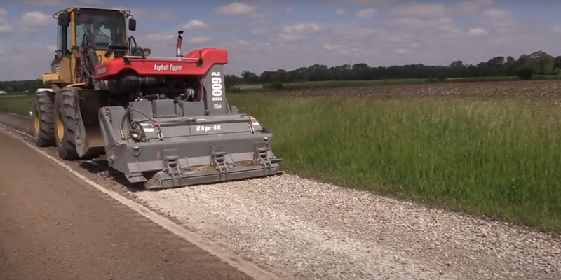 A tractor paving the side of a road.