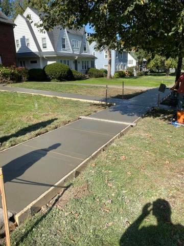 Freshly poured concrete sidewalk drying in a suburban neighborhood on a sunny day.