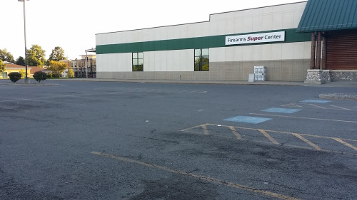Empty parking lot in front of a store with a Firearms Super Center sign on the building.
