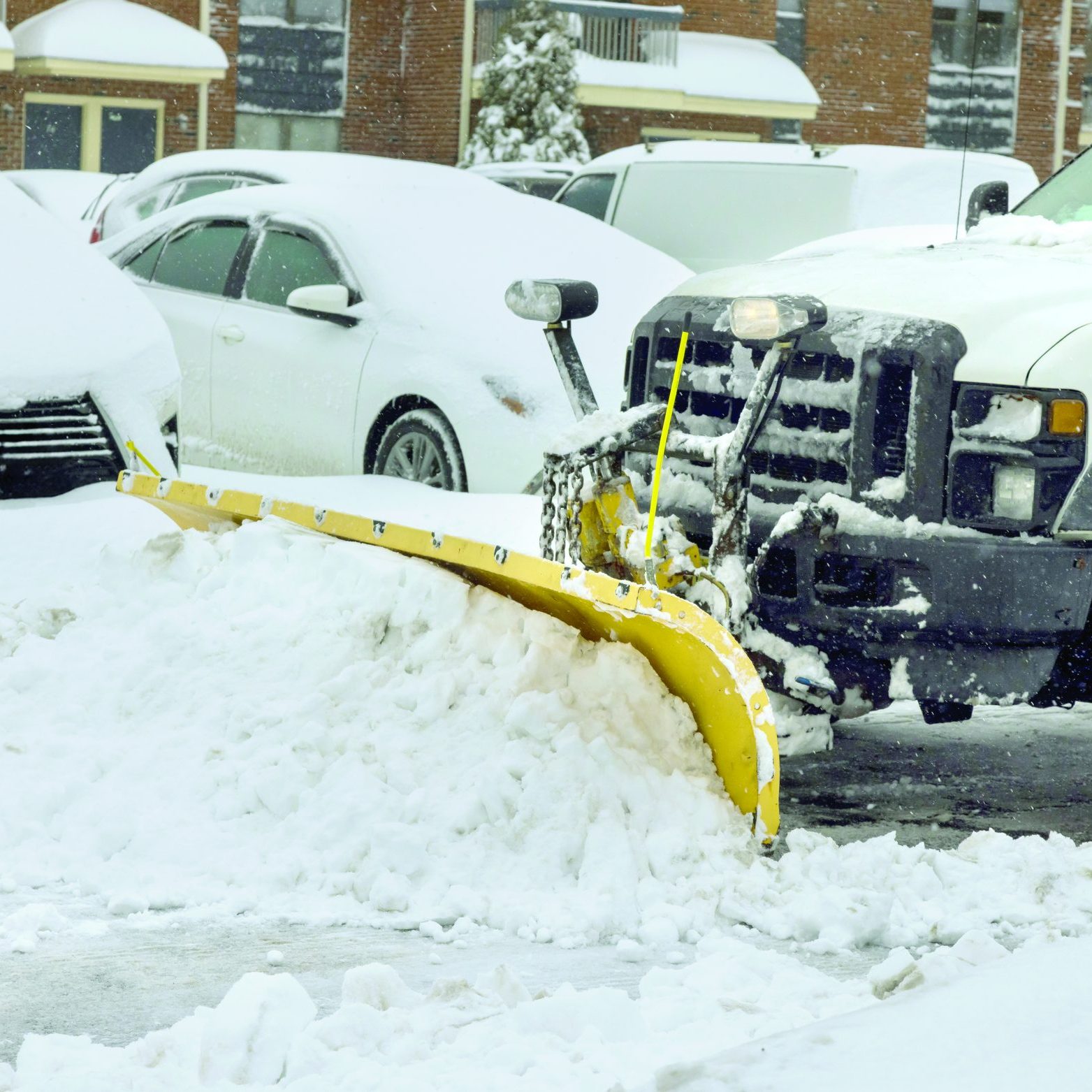 Snowplow truck removes snow from parking lot