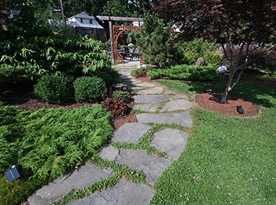 A beautiful garden along Irondequoit Garden Walks featuring vibrant flowers and a welcoming garden path.