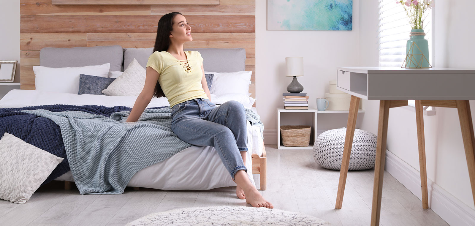 Woman sitting on bed in bright, modern bedroom