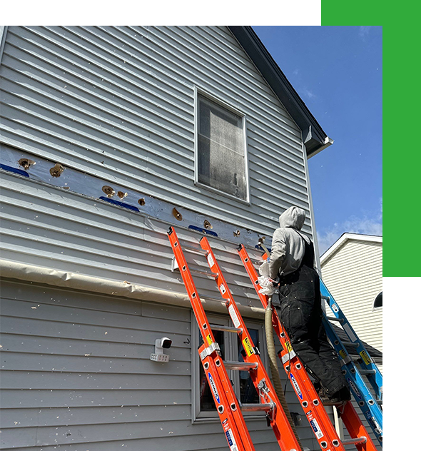Person on ladders repairing damaged siding on a two-story house under a partly cloudy sky.