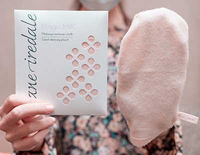 A person holds a package of Magic Mitt makeup remover and a beige cleansing mitt.