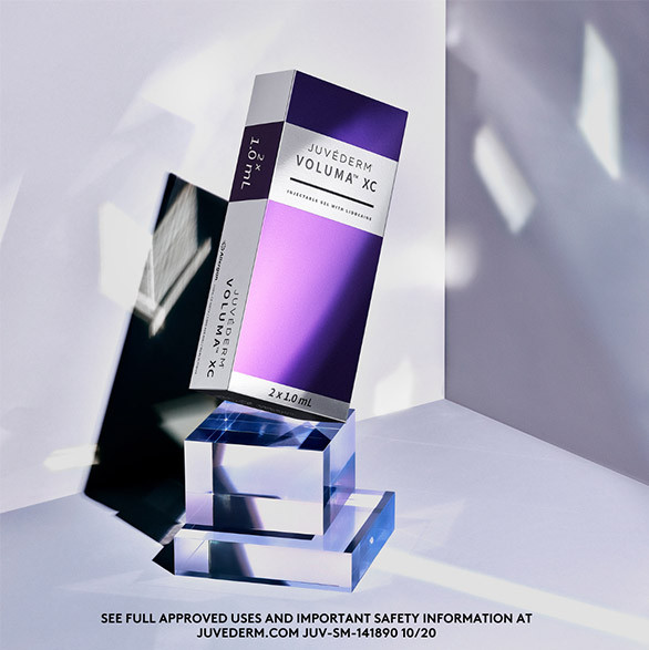 A Juvederm Voluma XC box stands on glass blocks with soft purple and white lighting.