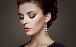 Beautiful woman with makeup on and long diamond earings gazing downward