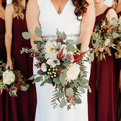 bride holding a bouquet, surrounded by bridesmaids in burgundy dresses
