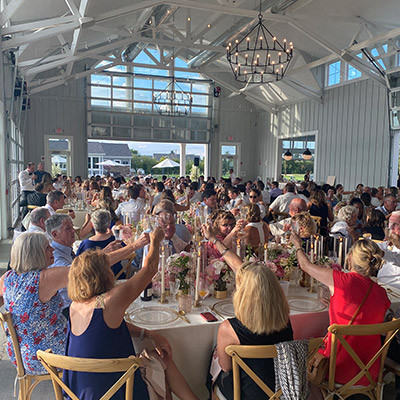 guests raise glasses in a bright, crowded wedding reception with rustic decor