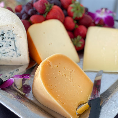 cheese platter with various cheeses, strawberries, grapes, and a knife on the side