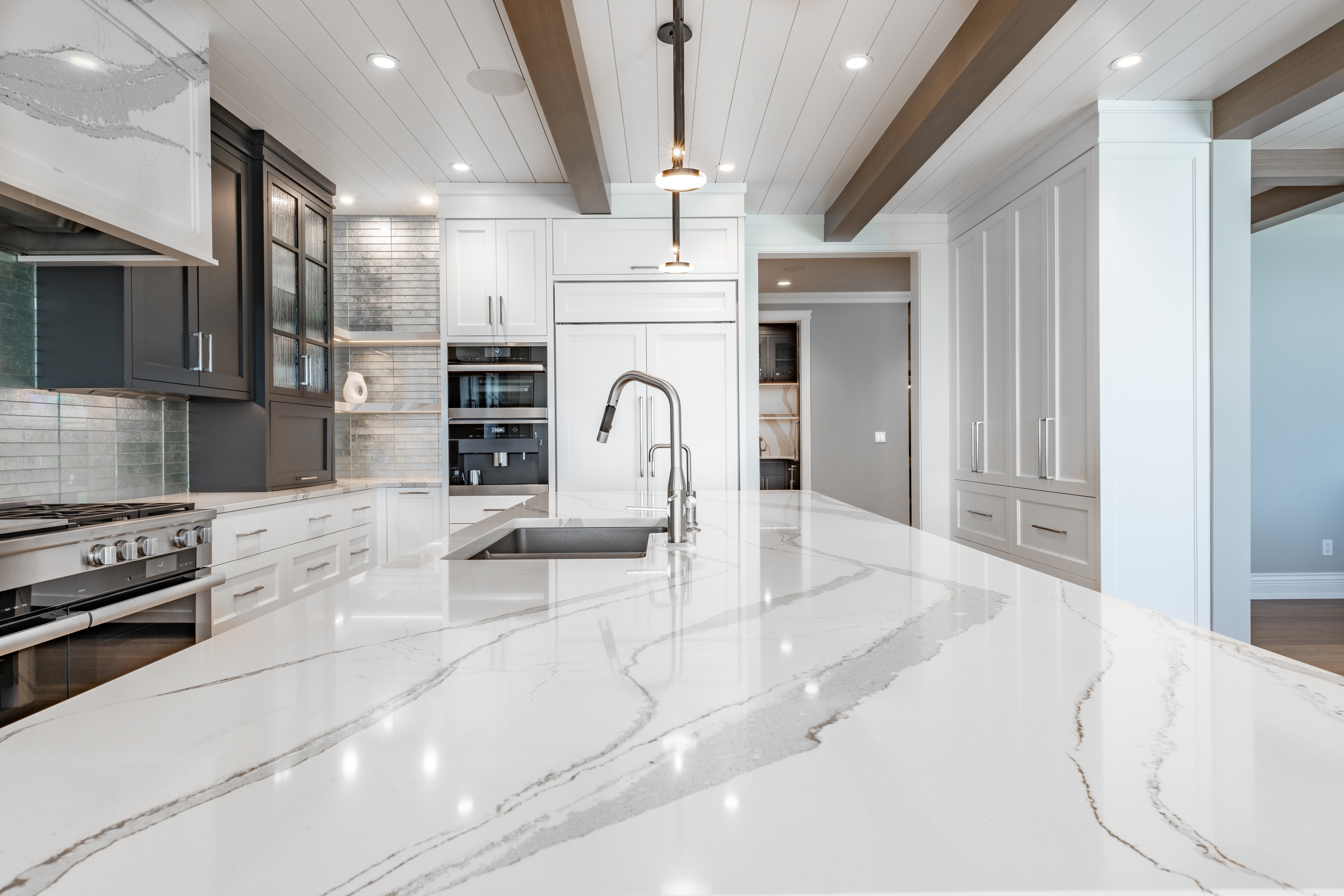 Modern kitchen with a large white marble island, sleek cabinets, and stainless steel appliances.