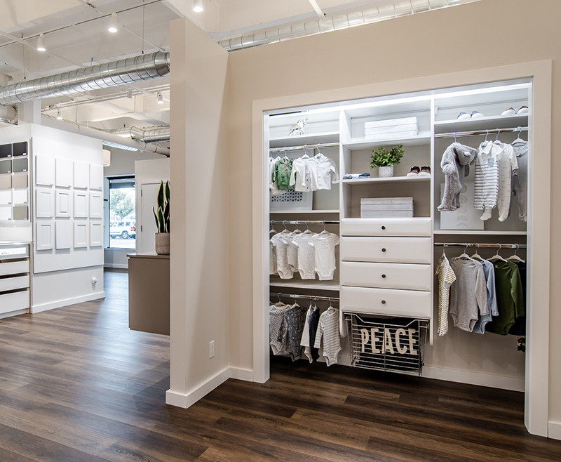 Modern walk-in closet with organized shelves, hanging clothes, drawers, and folded towels.