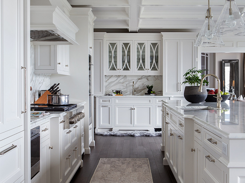 Bright, modern white kitchen with marble countertops, island, and stainless steel appliances.