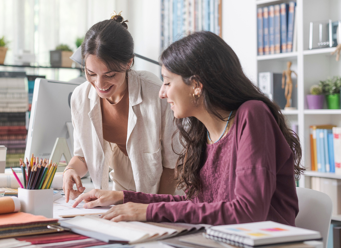 Two women at a desk smiling.