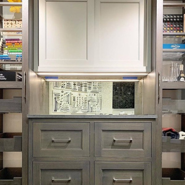 A gray cabinet with drawers, shelves, and organized sewing or craft supplies on display.