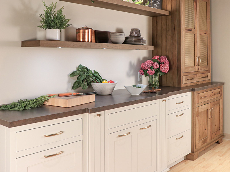 Modern kitchen with white cabinets, wooden shelves, fresh vegetables, and pink flowers.