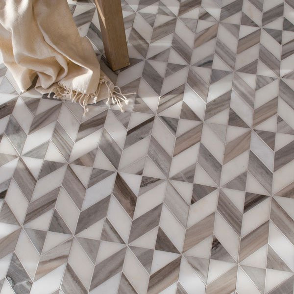 Geometric patterned tile floor in gray and white, with a beige cloth and wooden table leg.