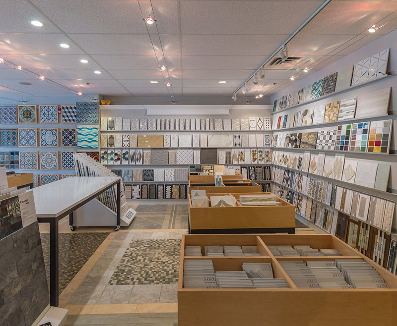 Tile showroom with displays of various wall tiles and samples arranged on shelves and tables.