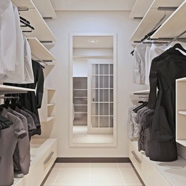 Modern walk-in closet with organized shelves, hanging clothes, and a large mirror at the end.