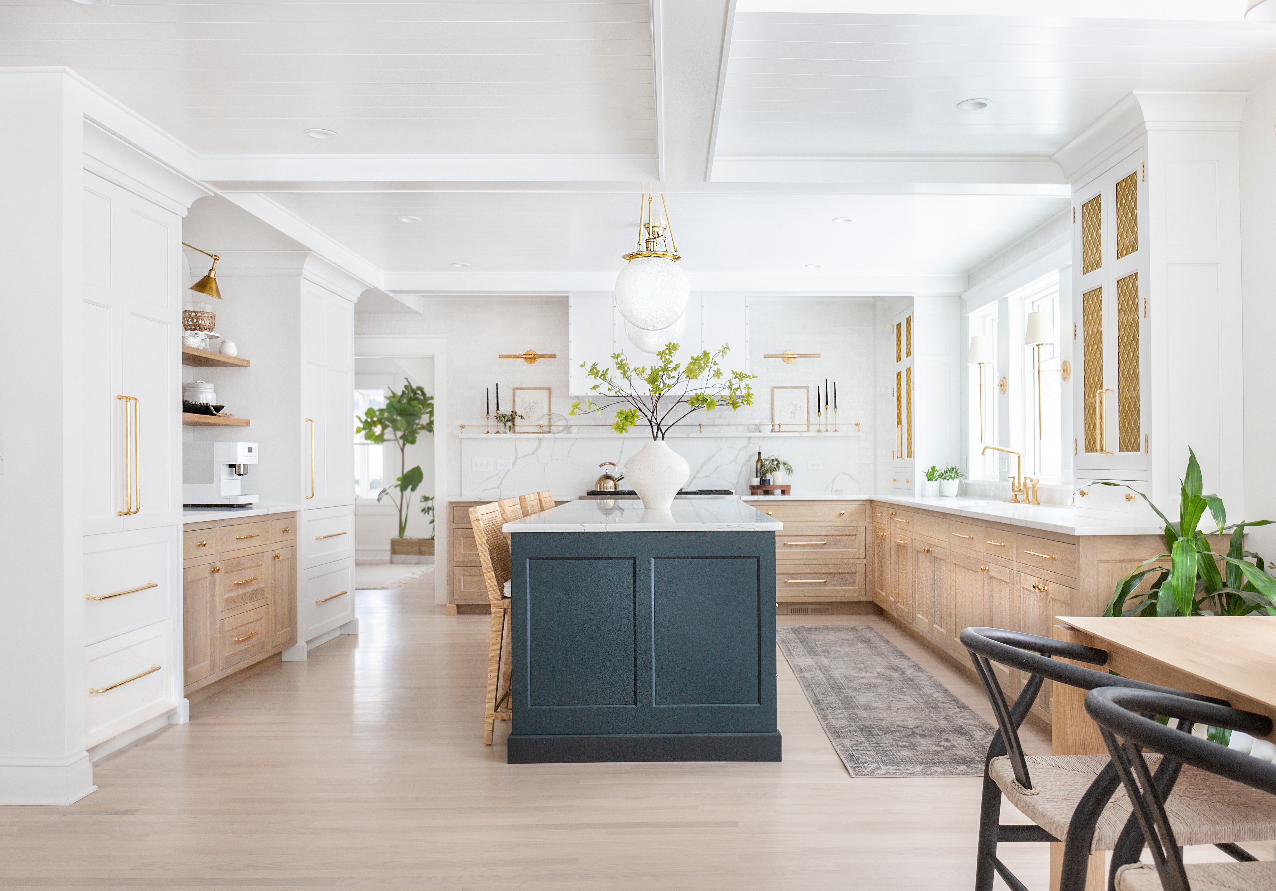 Bright, modern kitchen with wood accents, white cabinets, and a dark island with a vase.