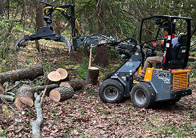 Person operating a compact loader moving cut logs