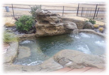 large faux rock spa with waterfall in backyard