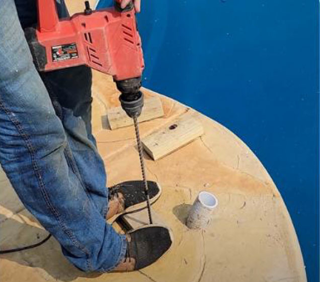 man drilling hole in concrete for rock waterfall pool install