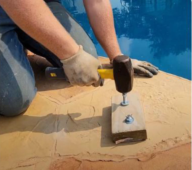 man hammering concrete for rock waterfall pool install