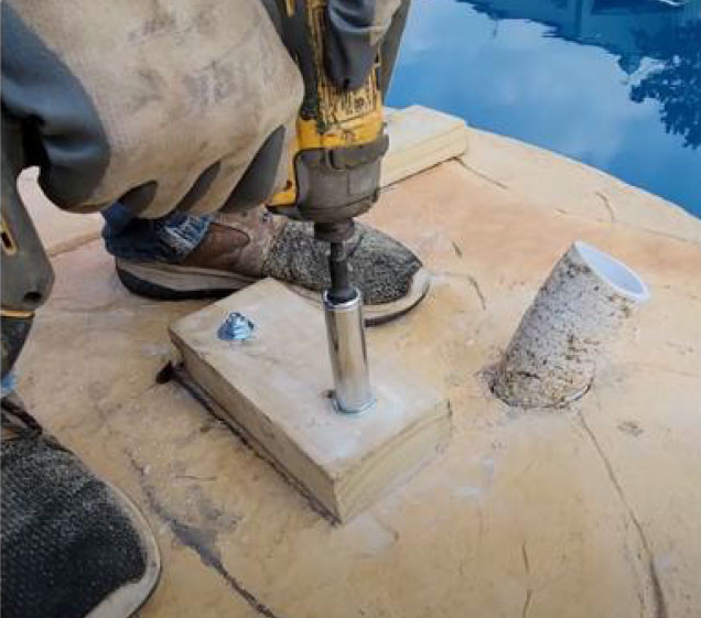 man drilling concrete for rock waterfall pool install