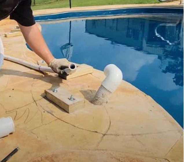 man fitting pipes for rock waterfall install on swimming pool