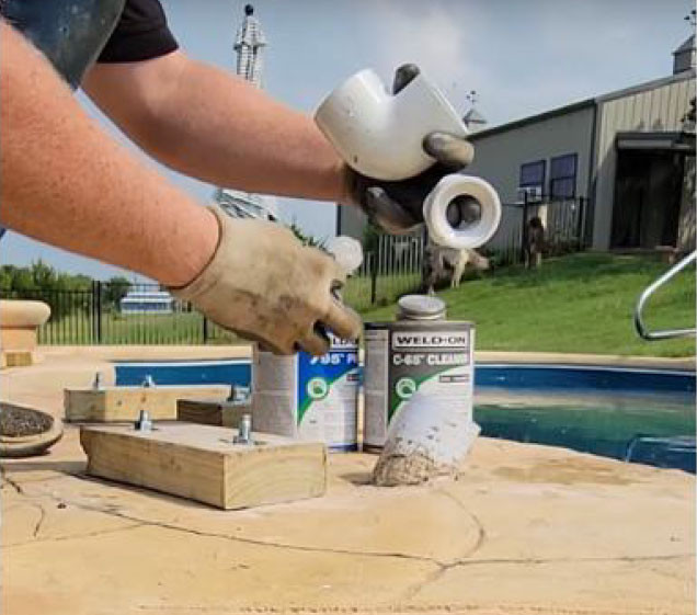 hand showing piping and glue for rock waterfall install on pool
