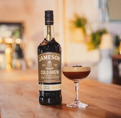 Jameson Cold Brew bottle and a cocktail glass on a wooden table.