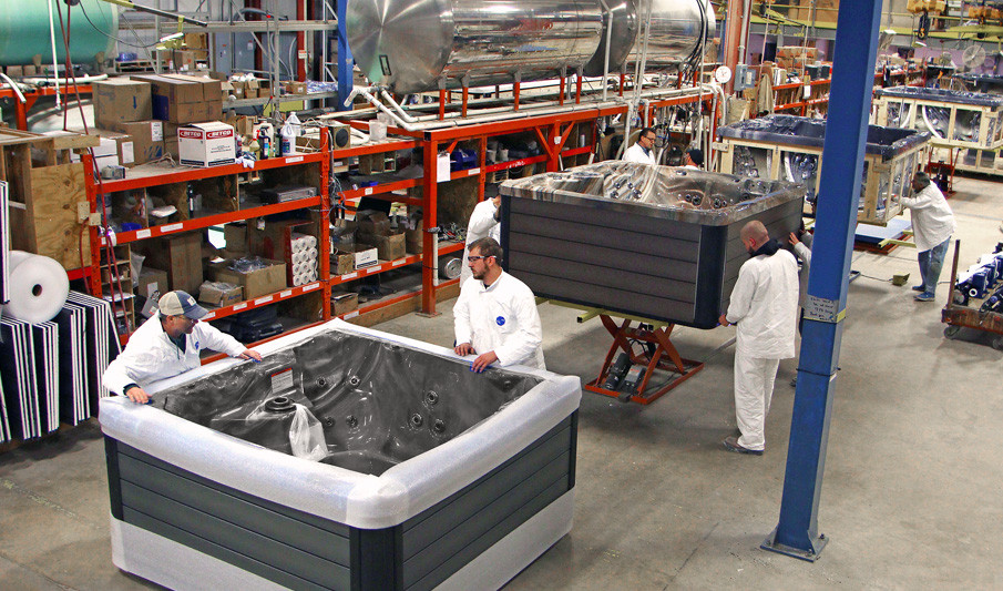 manufacturing line of hot tubs with men plumbing the hot tub units