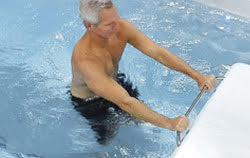 man in truswim swim spa working out holding on to aquabar