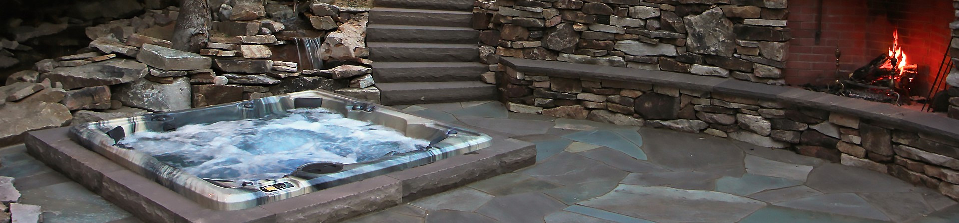 pdc spas premium series hot tub inground on stone patio with fireplace