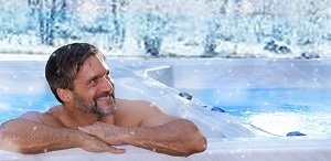 man relaxing in dual zone swim spa in winter